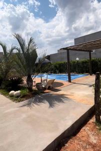 eine Terrasse mit einer Palme und einem Pool in der Unterkunft Rancho condomínio Terras d barra 