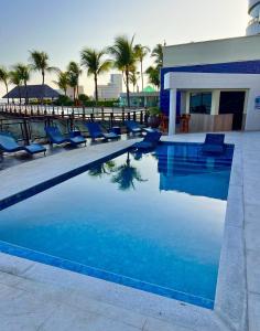 a swimming pool with blue chairs and palm trees at Flat no Iate Plaza Hotel in Fortaleza