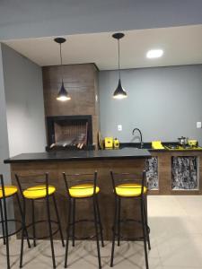 TRIPLEX COM SALÃO DE FESTAS À 1.3 KM DA PRAIA في بيساراس: مطبخ مع بار بأربعة كراسي