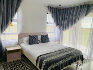 a bedroom with a bed with blue curtains at MILANI SEA VIEW in Kentani