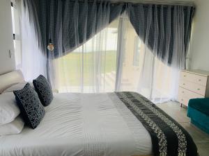 a bed in a bedroom with a large window at MILANI SEA VIEW in Kentani