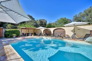 a swimming pool with an umbrella and chairs at Coco Banane in Anduze