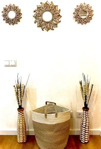 Tres jarrones con una cesta y dos espejos en una pared. en HM - HouseMirage, en Paço de Arcos