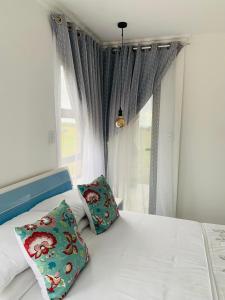 a bed with two pillows sitting next to a window at MILANI SEA VIEW in Kentani