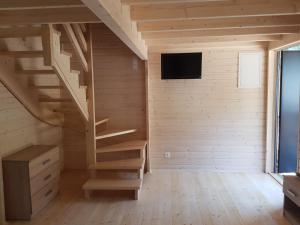 een kamer met een houten trap en een televisie bij Domek na Barcowej in Ostrowo