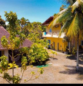 a resort with a yellow building and palm trees at Pousada e Hostel Recanto das Estrelas in Marau