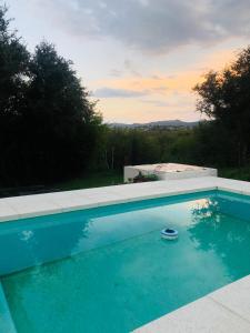 a blue swimming pool with a sunset in the background at Casa amplia con pileta in Villa Parque Siquiman