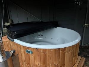 een groot houten bad met een zwarte top bij Comfortabele woning aan het water, hottub & kachel in Zuidlaren