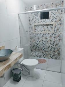 uma casa de banho branca com um WC e um chuveiro em Casa em Pradim de açúcar em Prado