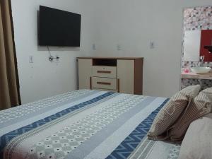 Un dormitorio con una cama con un televisor en la pared. en Casa em Pradim de açúcar, en Prado
