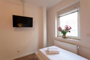 um quarto com uma televisão na parede e uma janela em City Apart Hannover em Hanôver