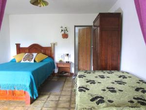 ein Schlafzimmer mit einem Bett, einer Kommode und einem Bett sidx sidx in der Unterkunft Alojamiento Rural Jardín Consentido in Jardin