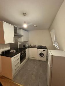 a small kitchen with white cabinets and a stove at Leicester Studio at City Centre with free parking in Leicester