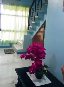 a vase with purple flowers on a table next to a staircase at JB Home sweet home Perfect for Family & Friends in Babag