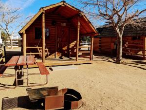 a wooden cabin with a table and a bench at Kingman KOA in Kingman