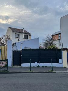 una cerca negra frente a una casa blanca en Le Petit Colombes en Colombes