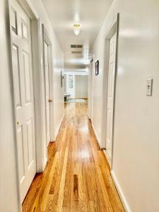 an empty hallway with white walls and wooden floors at Stylish Evergreen Apartment By Newark Airport in Newark