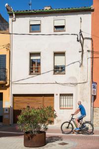 un hombre montando una bicicleta delante de un edificio en Ca la Roseta, en Sant Pere Pescador