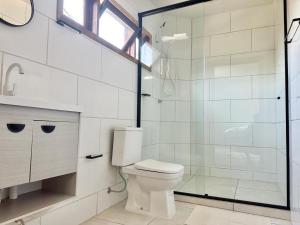 een badkamer met een toilet en een glazen douche bij Suíte na casa amarela in Pomerode