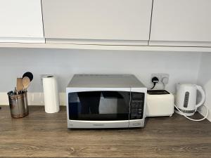 a microwave sitting on top of a kitchen counter at Remarkable 1-Bed Outhouse Studio in Dagenham in Dagenham