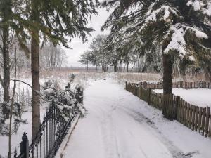 a snow covered path with a fence and trees at Willa widok na jezioro i las Swornegacie in Małe Swornigacie