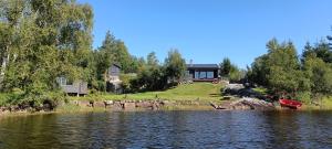 a house on the shore of a lake with a boat at Gauvik - Lyngdal in Lyngdal
