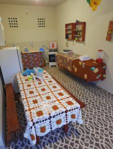 a room with a bed and a table with a quilt at ITAÚNAS Pousada Nossa Palhoça in Itaúnas