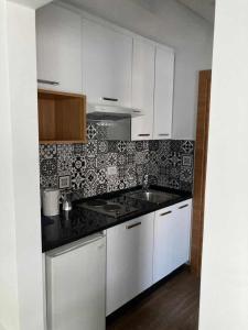 Una cocina con gabinetes blancos y una encimera negra. en Jade au cœur de la Marsa plage, en La Marsa 4 fotos más