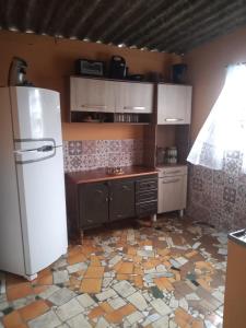 a kitchen with a refrigerator and a tile floor at Quarto em Caraguatatuba litoral norte in Caraguatatuba