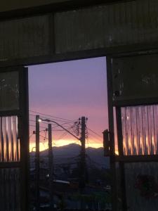 a view of a sunset through a window at Quarto em Caraguatatuba litoral norte in Caraguatatuba