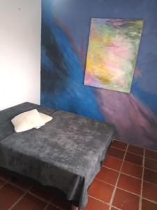 a room with a bed and a painting on the wall at Quarto em Caraguatatuba litoral norte in Caraguatatuba