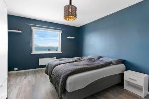 a blue bedroom with a bed and a window at koselig sentrum leilighet. in Ålesund