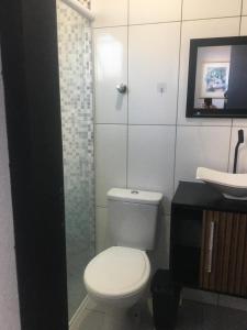 La salle de bains est pourvue de toilettes, d'une douche et d'un lavabo. dans l'établissement Sobrados Varuna, à Passo de Torres