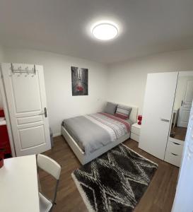 um pequeno quarto com uma cama e uma porta branca em 2 PIECES proche du centre PARIS 15 min em Rosny-sous-Bois