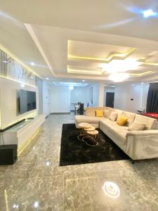 a large living room with a couch and a tv at Luxury 3BR + 3.5bath apartment in Victoria Island with pool in Lagos