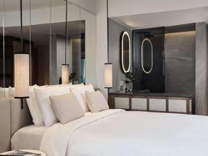 a bedroom with a large white bed and mirrors at NIKO Seaside Resort MGallery in Agios Nikolaos