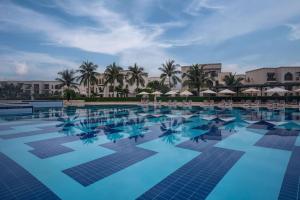 a large swimming pool with chairs and umbrellas at Salalah Rotana Resort in Salalah