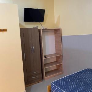 1 dormitorio con armario con espejo y TV en Residencial Carloz, en Tarapoto