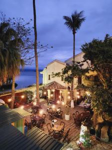 a patio with tables and chairs and palm trees at night at Hostel Jardim das Bruxas 410 in Florianópolis