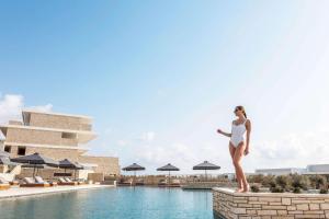 a rendering of a woman standing on a wall next to a swimming pool at Cap St Georges Hotel & Resort in Peyia