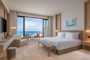 a bedroom with a bed and a view of the ocean at Cap St Georges Hotel & Resort in Peyia