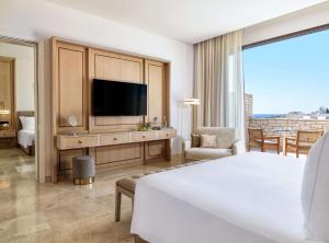 a hotel room with a bed and a television at Cap St Georges Hotel & Resort in Peyia