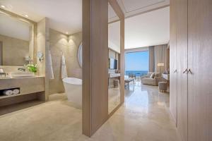 a bathroom with a tub and a sink and a mirror at Cap St Georges Hotel & Resort in Peyia