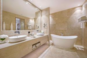 a bathroom with two sinks and a large mirror at Cap St Georges Hotel & Resort in Peyia
