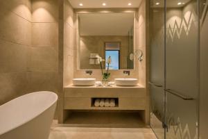 a bathroom with two sinks and a tub and a mirror at Cap St Georges Hotel & Resort in Peyia