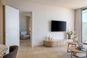 a living room with a tv on a white wall at Cap St Georges Hotel & Resort in Peyia