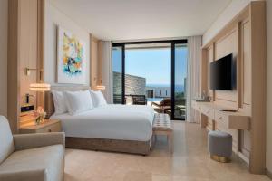 a bedroom with a bed and a tv and a couch at Cap St Georges Hotel & Resort in Peyia