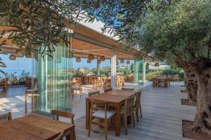 a restaurant with wooden tables and chairs and a tree at Cap St Georges Hotel & Resort in Peyia