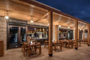 a restaurant with wooden tables and chairs on a patio at Cap St Georges Hotel & Resort in Peyia