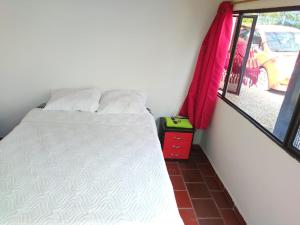 a small bedroom with a bed and a window at Hotel Chimeneas del Dorado in Sesquilé